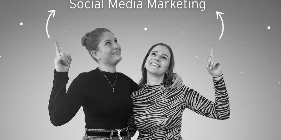 Foto von Anja und Melanie wie die nach oben zeigen auf "Social Media Marketing"