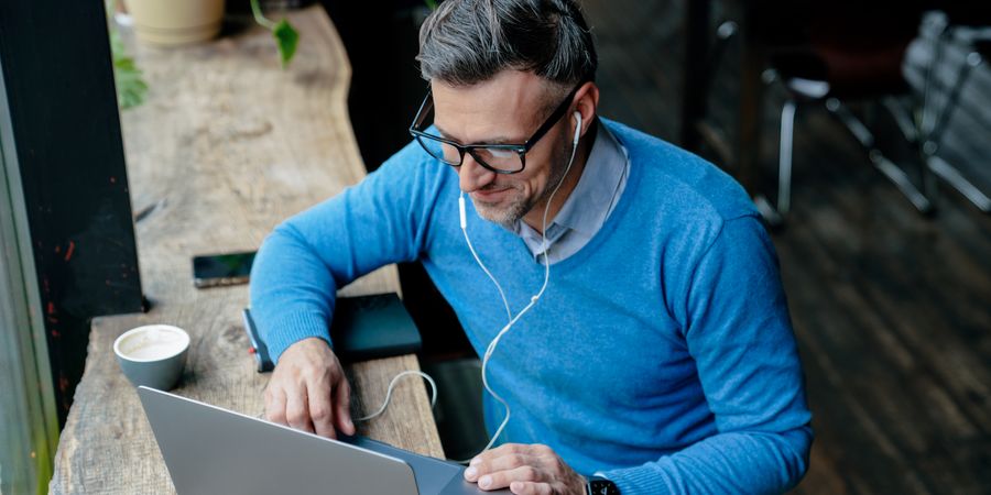 Foto von Mann mit Kopfhörern und Laptop am arbeiten 