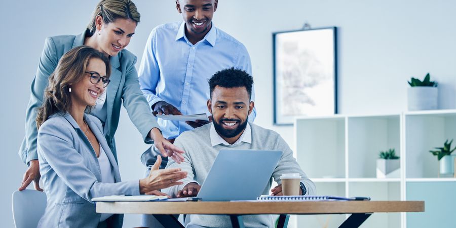 Foto von Team vor Laptop, lachend | Projektkommunikation