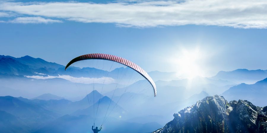 Foto eines Gleitschirmfliegers über den Bergen