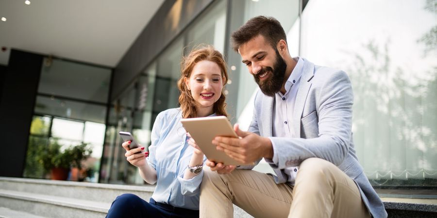 Foto von einem Mann und einer Frau, die in ein Tablet schauen | Videotrainings & Online-Jobbörse
